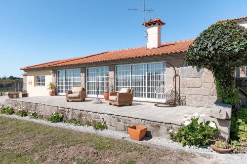a house with a patio with two chairs and a tree at A Casinha in Vila Nova de Famalicão