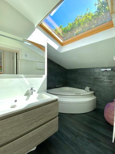 La salle de bains est pourvue d'un lavabo, d'une baignoire et d'une fenêtre. dans l'établissement Le Bout du Monde, à Saint-Léonard