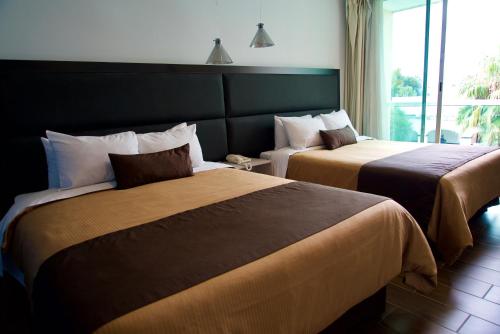 2 camas en una habitación de hotel con ventana en Hotel Posada Señorial en Cholula