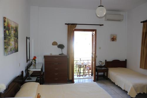 a bedroom with two beds and a desk and a window at Michalis Studios in Lipsoi