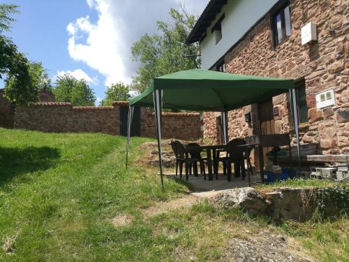 una mesa y sillas bajo una sombrilla verde en Casa Soleta Ezcaray en Ezcaray