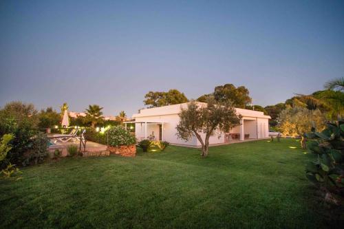 a house with a green yard with a tree at Pietre Rosse Sicule - case vacanze Elena e Marta in Montevago