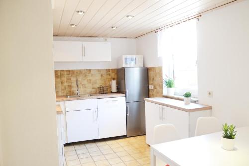 eine Küche mit weißen Schränken und einem Kühlschrank aus Edelstahl in der Unterkunft #Hoenepartment - TimeOut Waldhessen - bis zu 8 Pers. in Hönebach