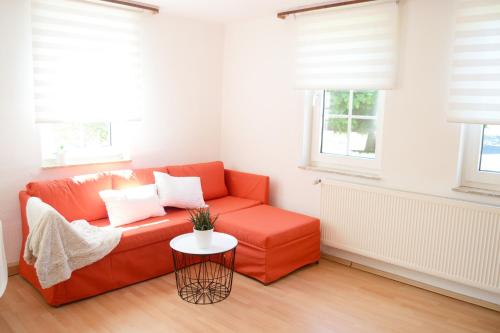 an orange couch in a living room with windows at #Hoenepartment - TimeOut Waldhessen - bis zu 8 Pers. in Hönebach
