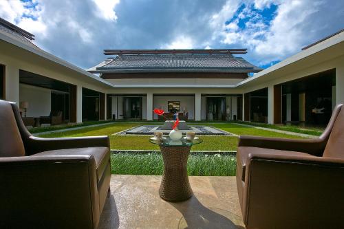 a patio with chairs and a table in front of a building at Narada Resort & Spa Perfume Bay Sanya - All Villas in Lingshui