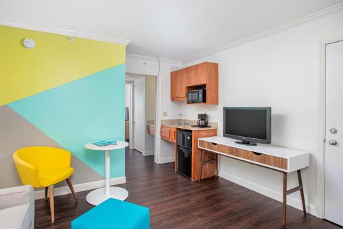 a small room with a kitchen with a tv at Beachside Hotel & Suites Cocoa Beach - Port Canaveral in Cocoa Beach