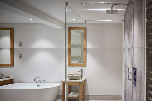 a bathroom with a white tub and a shower at Barnett Hill Hotel in Guildford