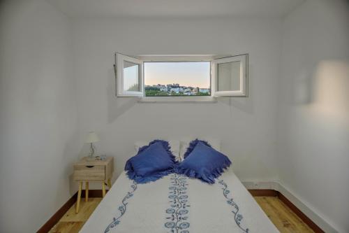 ein Schlafzimmer mit einem Bett mit blauen Kissen und einem Fenster in der Unterkunft casa do lago in Setúbal