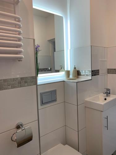a white bathroom with a sink and a mirror at Apartamenty Zieleniec-Julia 3 in Duszniki Zdrój