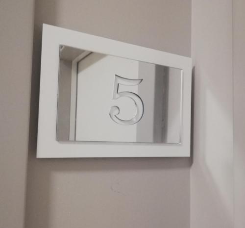 a white lightswitch on a wall with the number five at APARTAMENTY POSEJDON in Świnoujście
