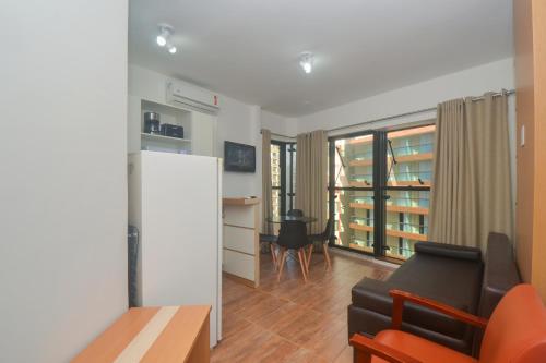 een woonkamer met een bank, een stoel en een koelkast bij Flat Gonzaga Praia in Santos