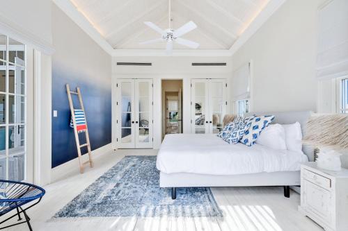 a bedroom with a white bed and a blue wall at Ambergris Cay - Private Island All-Inclusive in Big Ambergris Cay