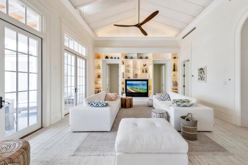 a living room with white furniture and large windows at Ambergris Cay - Private Island All-Inclusive in Big Ambergris Cay