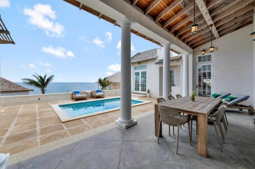 a patio with a table and chairs and a pool at Ambergris Cay - Private Island All-Inclusive in Big Ambergris Cay