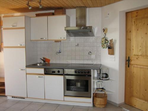 La cuisine est équipée de placards blancs et d'un four avec plaques de cuisson. dans l'établissement Er Liung - Ferienwohnung für max. 3 Personen, à Falera