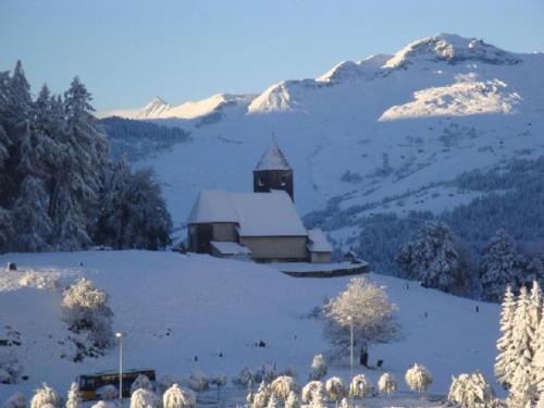 a church on a snowy hill with snow covered mountains at Er Liung - Ferienwohnung für max. 3 Personen in Falera