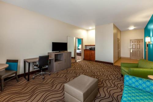 a hotel room with a desk and a couch and a table at La Quinta by Wyndham Midland North in Midland