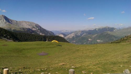 a yellow parachute on a green field with mountains at Hostal Rural Sositana in Castejón de Sos