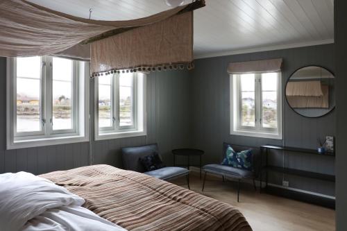 a bedroom with a bed and a mirror and windows at Solsiden Brygge Rorbuer in Ballstad