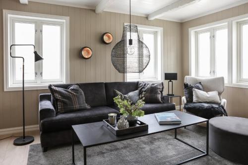 a living room with a black couch and a table at Solsiden Brygge Rorbuer in Ballstad
