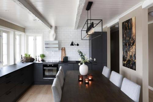 a kitchen with a wooden table and a kitchen with white appliances at Solsiden Brygge Rorbuer in Ballstad