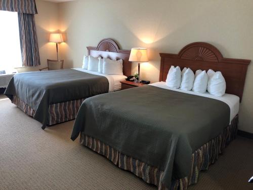 Una habitación de hotel con dos camas y dos lámparas. en Red Coach Inn & Suites, en Red Oak