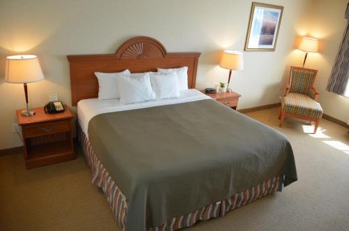 a hotel room with a large bed and a chair at Red Coach Inn & Suites in Red Oak