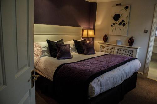 a bedroom with a bed with purple pillows at Langshott Manor - Luxury Hotel Gatwick in Horley