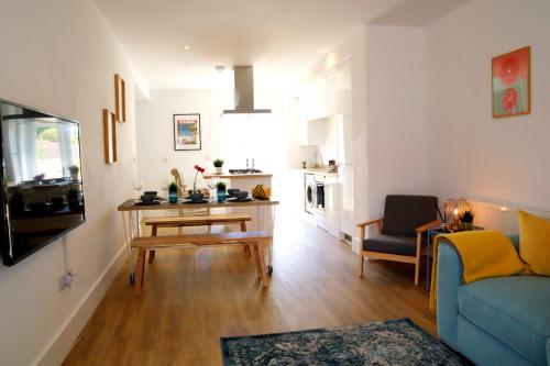 a living room with a blue couch and a table at Modern New House - Great Location - Garden - Parking - Fast WiFi - Smart TV - Stunning 2 Bedroom House sleeps up to 4! Only 5 mins drive to Sandbanks Beach in Parkstone