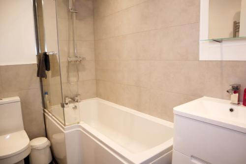 a bathroom with a shower and a tub and a toilet at Modern New House - Great Location - Garden - Parking - Fast WiFi - Smart TV - Stunning 2 Bedroom House sleeps up to 4! Only 5 mins drive to Sandbanks Beach in Parkstone