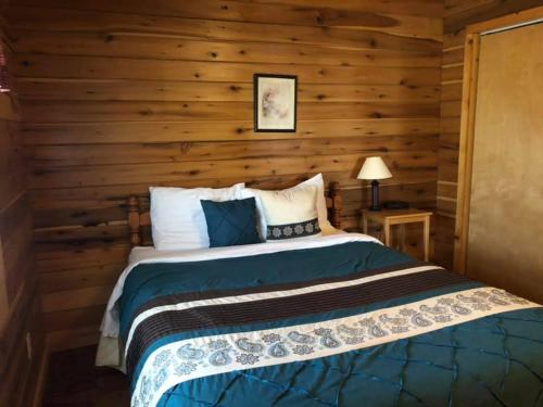 a bedroom with a bed with a wooden wall at Country Road Cabins in Hico