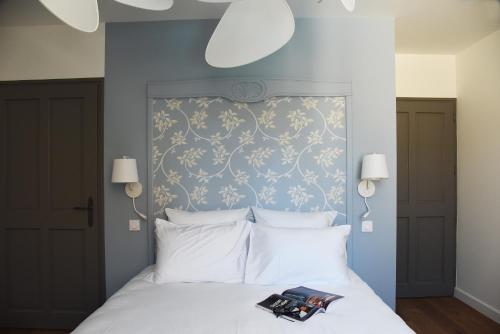 a bedroom with a white bed with a blue wall at Le Charles V in Meursault
