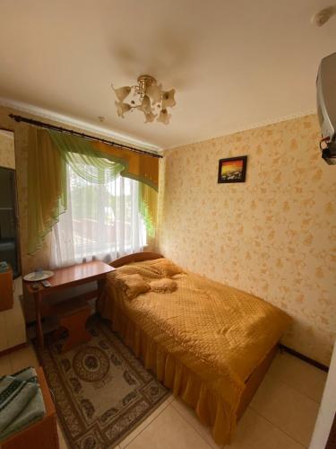 a bedroom with a bed and a table and a window at Золотий Лев in Zvenyhorodka