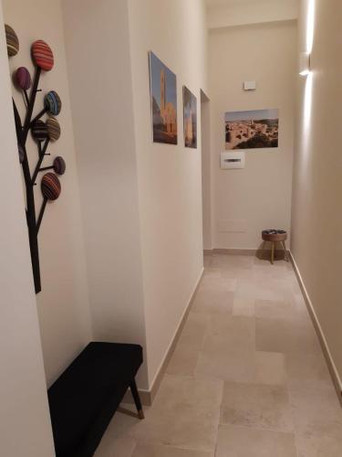 un pasillo con obras de arte en las paredes y un banco en Casa Pompelmo Rosa, en Bernalda