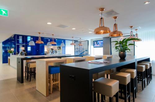 a kitchen with blue cabinets and a bar with stools at Holiday Inn Express Rotterdam - Central Station by IHG in Rotterdam