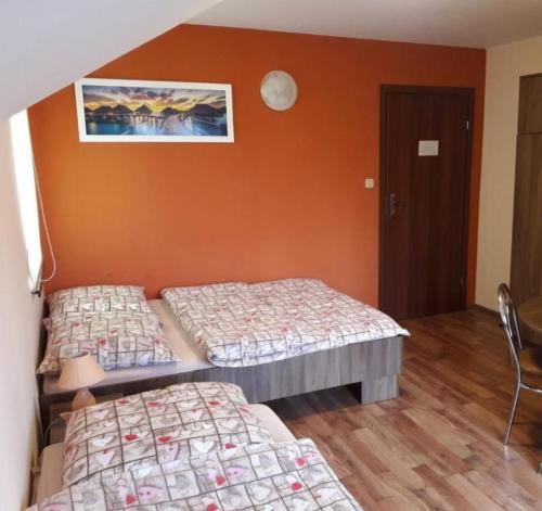 2 Betten in einem Zimmer mit orangefarbener Wand in der Unterkunft Albinos in Albigowa
