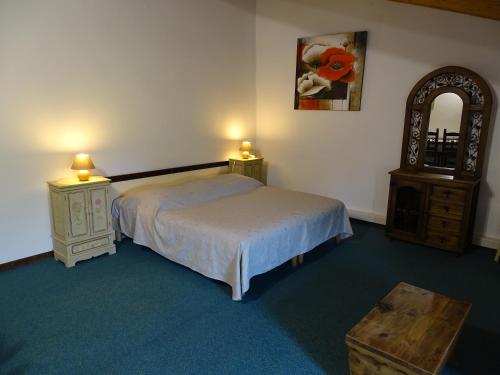 a bedroom with a bed and a dresser and a mirror at Hôtel Mas de l'Espaïre in Les Vans