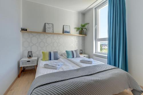 a bedroom with two beds with blue curtains and a window at Wave Apartments - SOLVO in Gdańsk