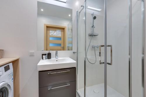 uma casa de banho com um lavatório e um chuveiro em Wave Apartments - SOLVO em Gdansk