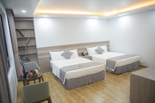 um quarto de hotel com duas camas e uma mesa e cadeiras em Bamboo Hotel em Thanh Hóa