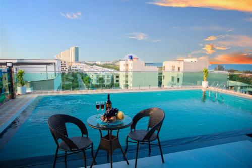 uma mesa com duas cadeiras e copos de vinho ao lado de uma piscina em Bamboo Hotel em Thanh Hóa
