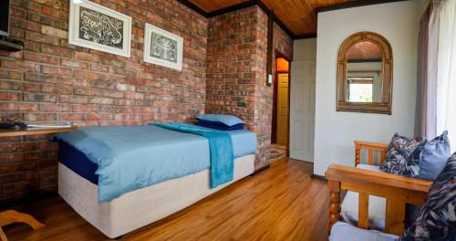 a bedroom with a bed and a brick wall at Palm Cottage - Colchester - 5km from Elephant Park in Colchester