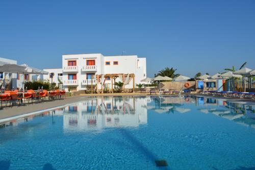una gran piscina con mesas y sombrillas junto a un edificio en Bouradanis Village Hotel en Marmari
