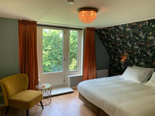 a bedroom with a bed and a chair and a window at B&B Pastorie Jelsum in Jelsum