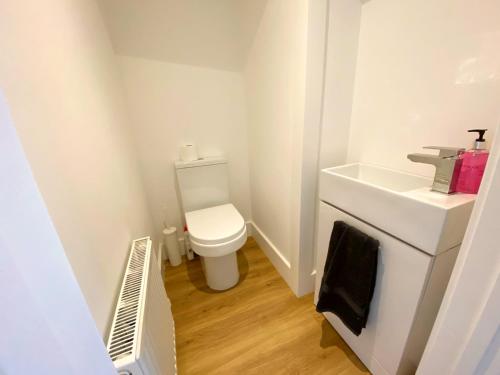 a small bathroom with a toilet and a sink at Stunning New House - Great Location - Garden - Parking - Fast WiFi - Smart TV - Beautiful 2 Bedroom House sleeps up to 6! Only 5 min drive to Sandbanks beach! in Parkstone