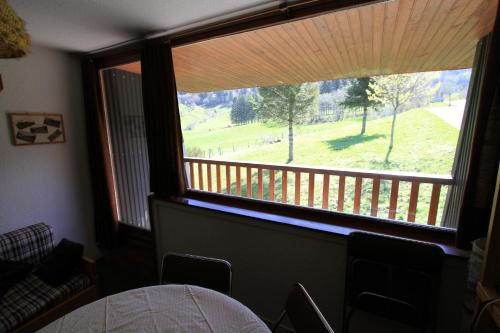 a room with a large window with a view of a yard at Studio Village des Longes in Le Mont-Dore