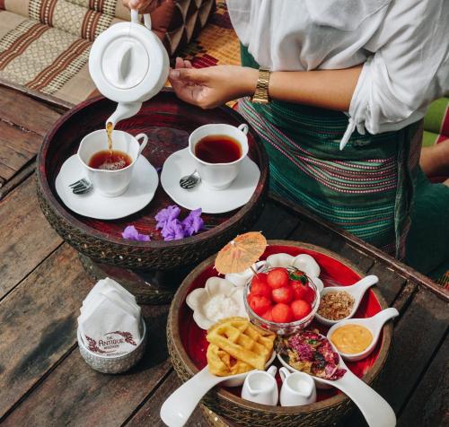 une femme verse du thé d'une théière sur un plateau de nourriture dans l'établissement The Antique Riverside Resort, à Ban Pong