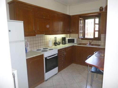 kuchnia z drewnianymi szafkami i białą płytą kuchenną w obiekcie Evgenia's House w mieście Kala Nera