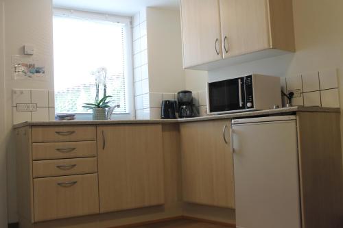 a kitchen with a white refrigerator and a microwave at Odense Apartments in Odense