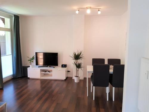 a living room with a table with chairs and a television at Apartmenthaus Luise in Bad Schandau